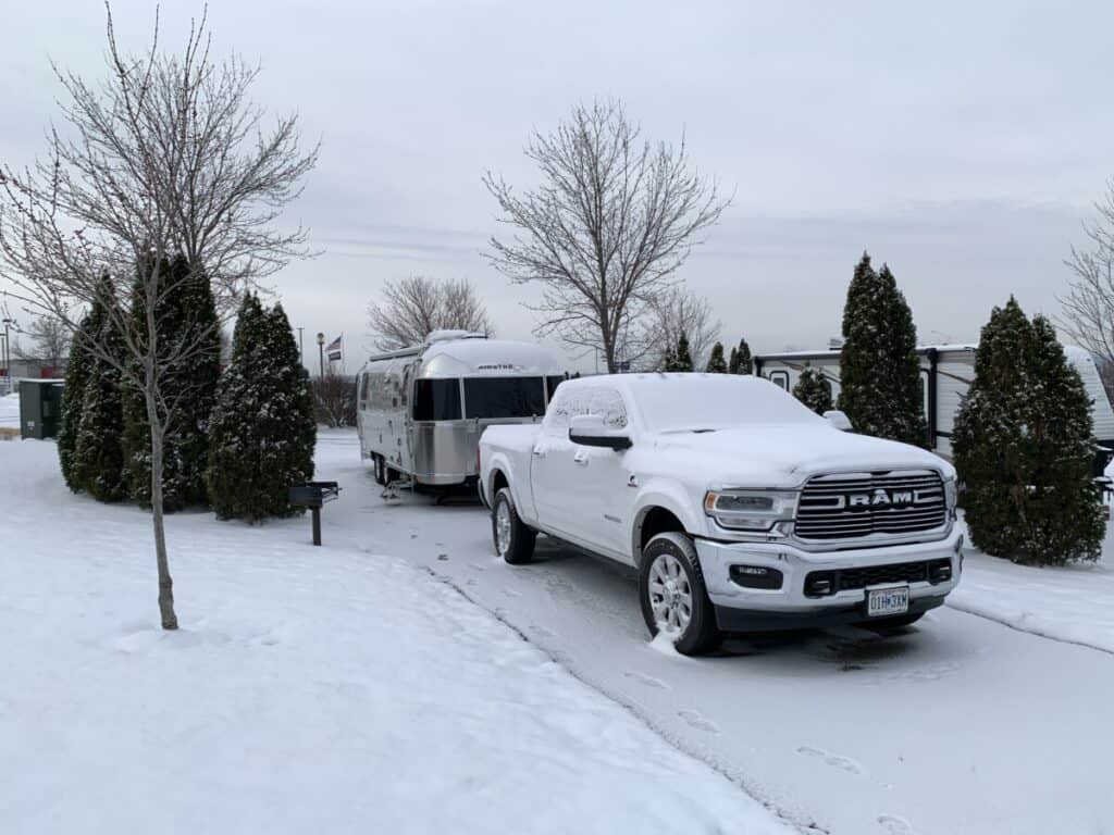 Image of a pickup truck and Airstream travel trailer covered in snow.